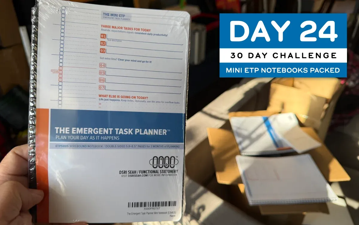 A 5.8x8.5 inch Emergent Task Planner notebook, shrinkwrapped, held in a hand by the edge to show it off (full size image)