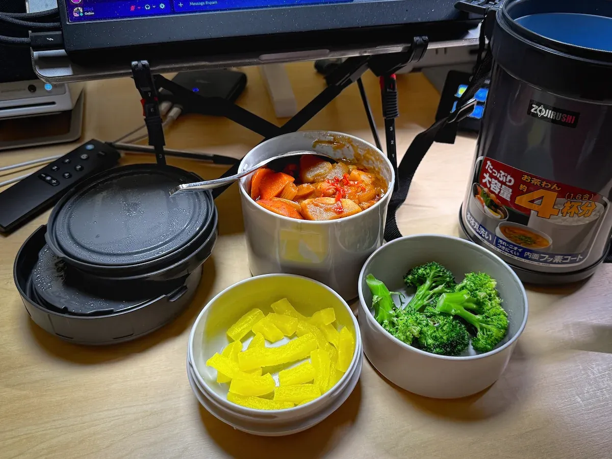 Three containers of food from a Mr Bento vacuum lunch jar. One contains yellow pickled daikon. One contains Japanese curry with rice. One contains blanched brocolli. (full size image)